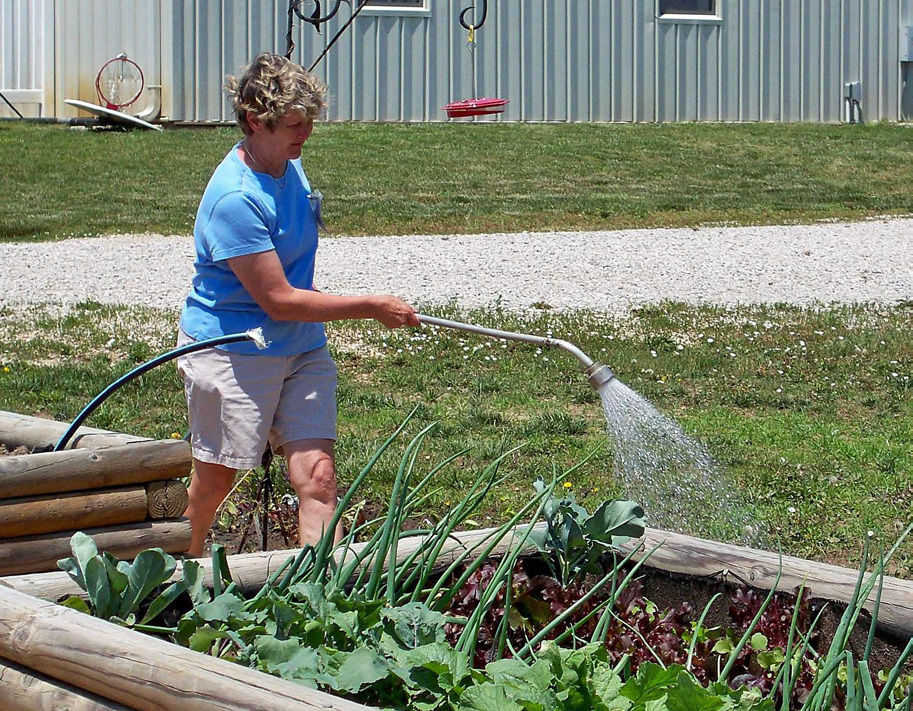 A woman waters a garden as part of a Tri-Valley project.