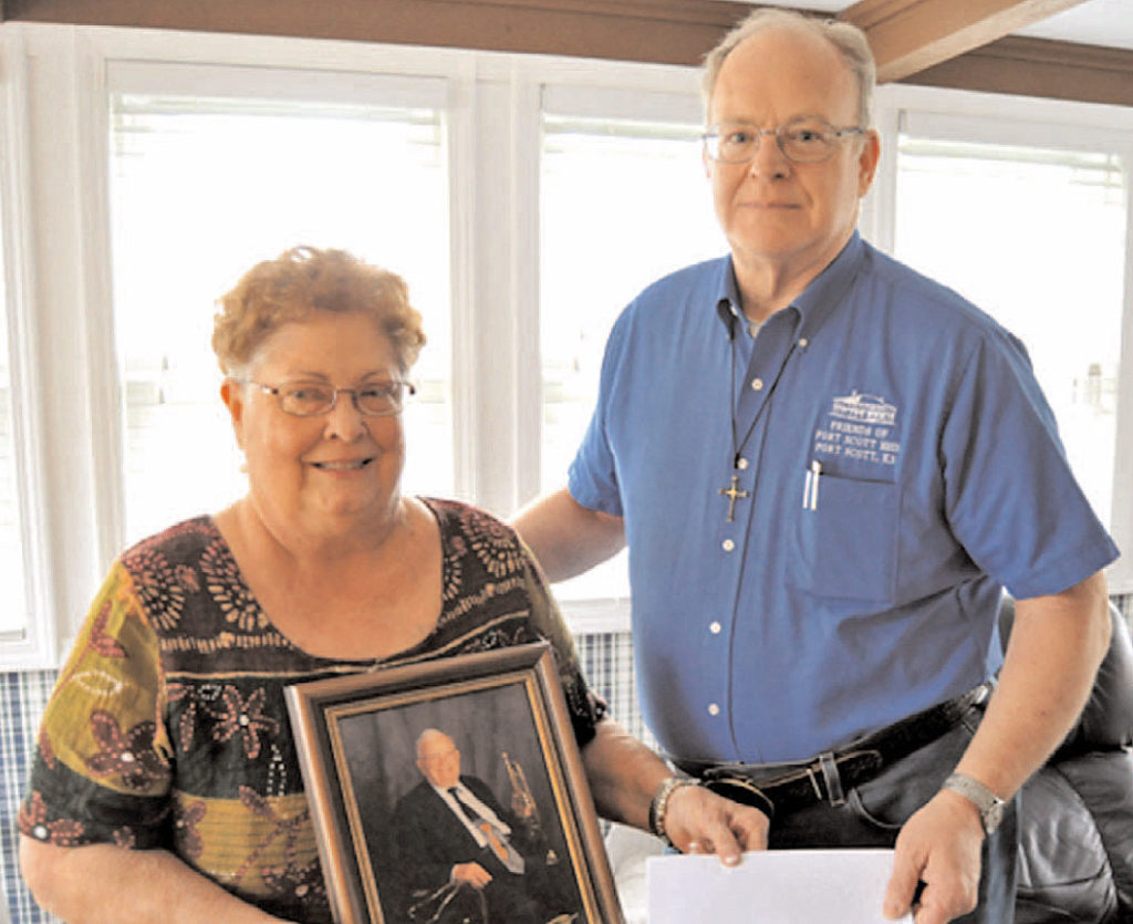 Janet (Irby) Braun holds a photo of her late father Pratt Irby while presenting a check to Reed Hartford of the Friends of Fort Scott National Historic Site.